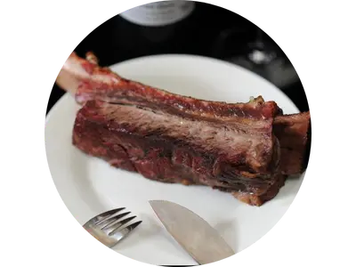 德州煙燻帶骨牛小排切面展示，呈現牛肉油脂與骨邊膠質口感