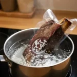 煙燻單骨牛小排與橫切牛小排真空包裝，正在鍋中進行隔水加熱，展示簡單即食的料理方式